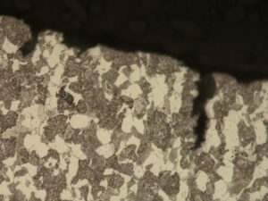 High magnification photomicrograph of the unetched cross-section along the fracture surface reveals axial corrosion penetrations, indicating active corrosion along the pre-existing crack.