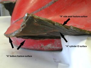 A close up photo of fracture side “A” near the cylinder bottom. The axial fracture surface displays multiple jogs resembling a stair-step appearance. The interior (ID) surface exhibits numerous cracks. These features are shown in closer views in subsequent figures.