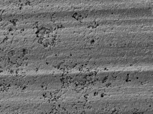 A low magnification SEM image of the cleaned surface showed localized patches of corrosion pitting.