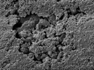 An increased magnification SEM view of the fitting’s internal surface showed the pitting effects from localized corrosion cells.