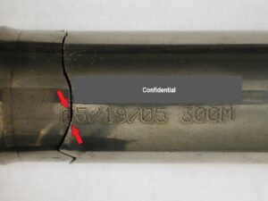 A close-up view of the fractured input shaft. The fracture crosses the "0" in the date code stamp on the part (arrows).